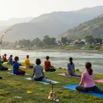Best yoga teacher training course in Rishikesh India, instructor leading diverse students in serene yoga practice by the Ganges at sunrise.